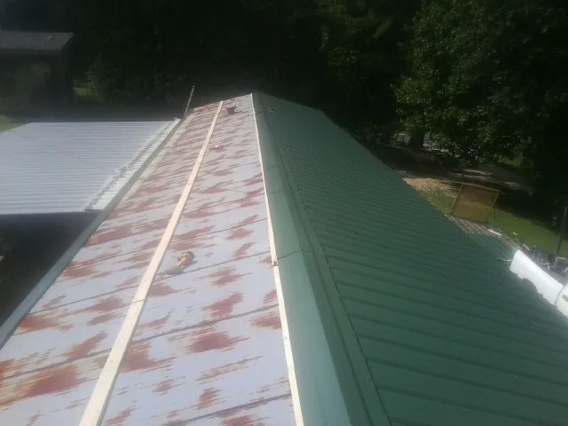 Old rusted panels beside newly installed green metal roofing — Wind Damage Roof Repair by Roofing Brothers in Exeter