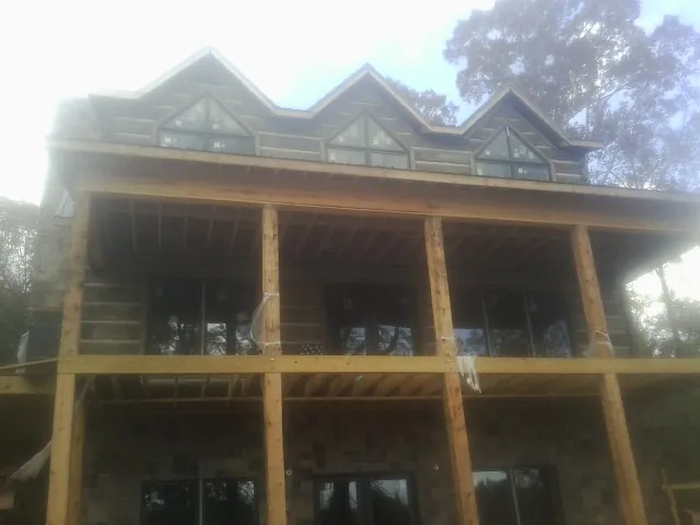 Dormers and porch framing on a large log home under construction — Roof Coating work by our crew in Exeter